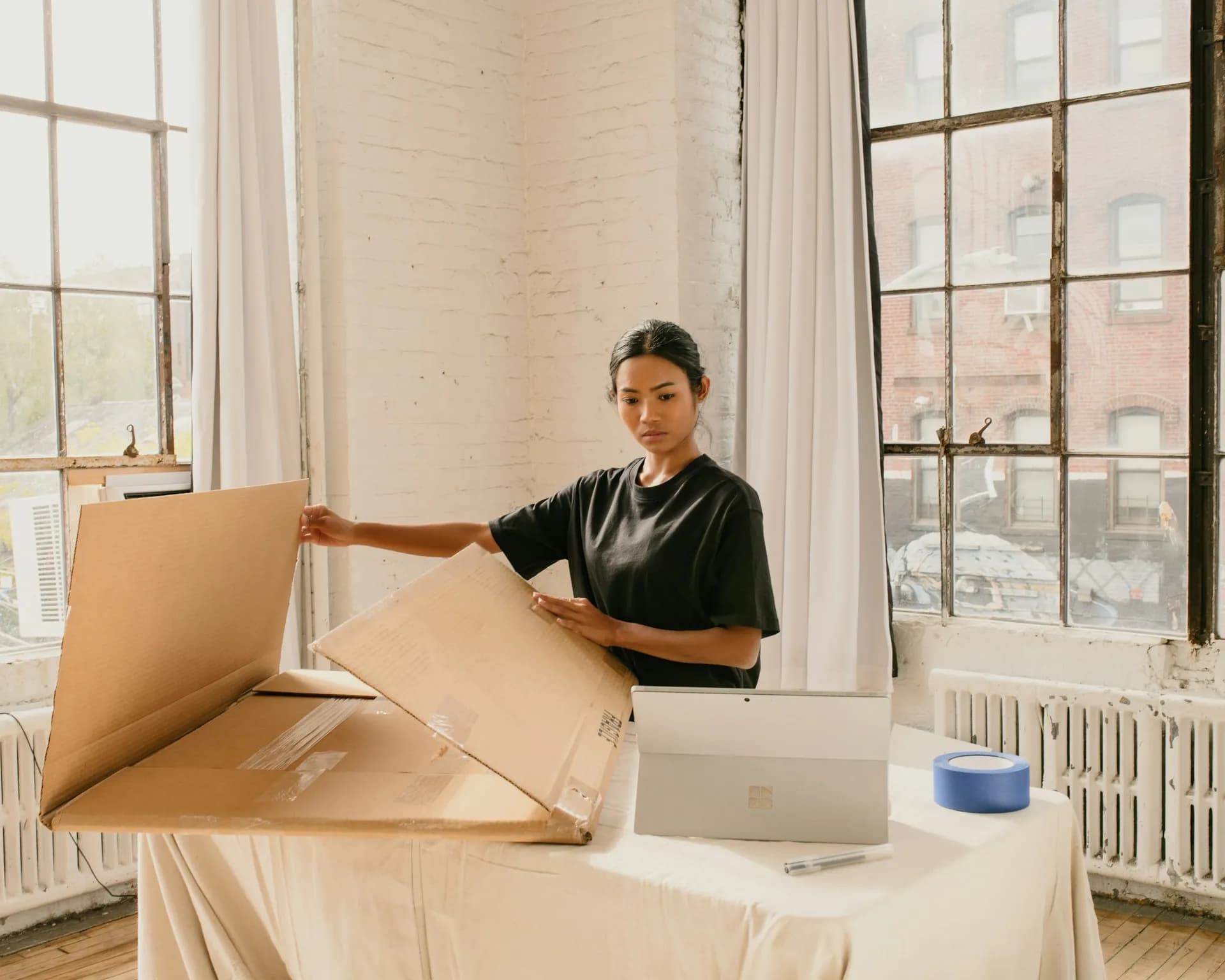 A seller folding a shipping box in a bright studio