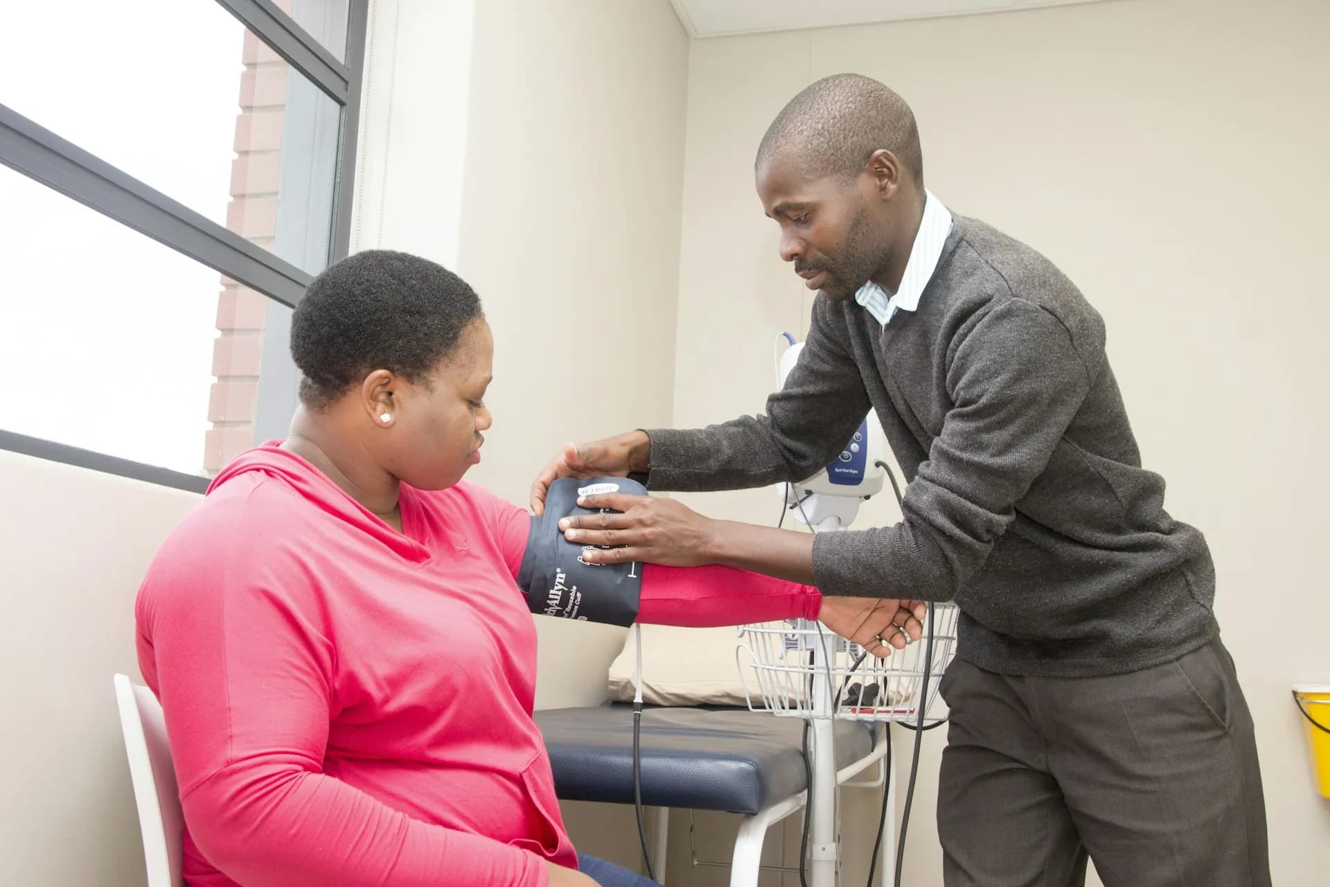 A clinician taking a patient's blood pressure in an exam room