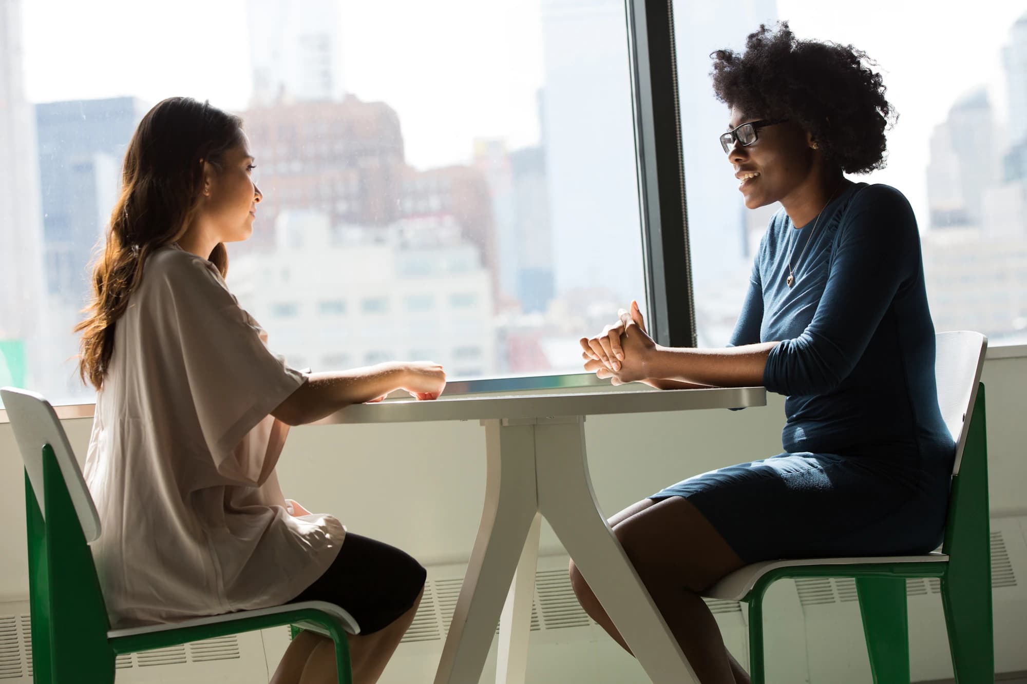 A recruiter interviewing a candidate by a city window