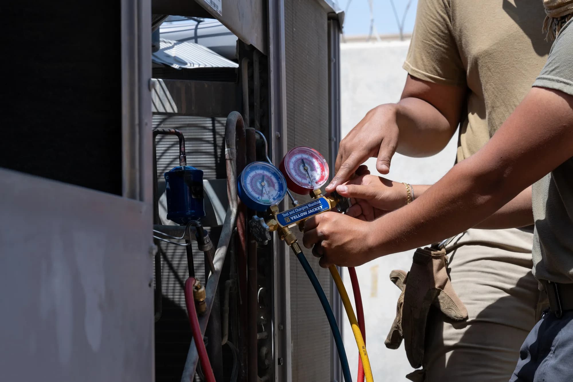 A technician connecting refrigerant gauges to an air conditioning unit