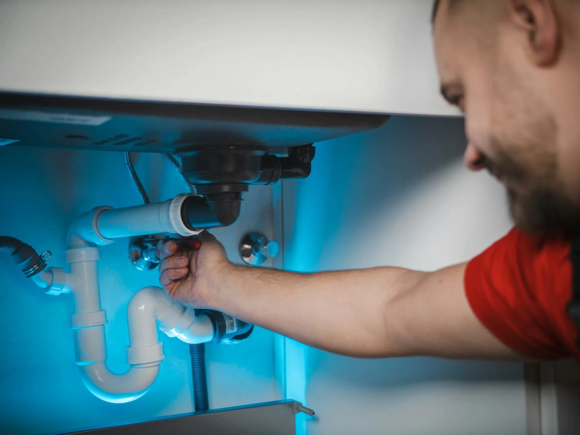A plumber fitting the trap under a sink