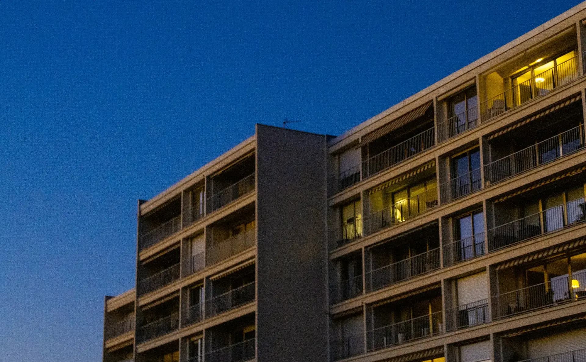 An apartment block at dusk with lit windows
